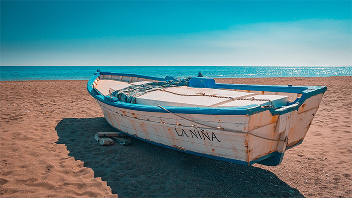 蓝色天空下沙滩上的木船超清唯美桌面屏保图片